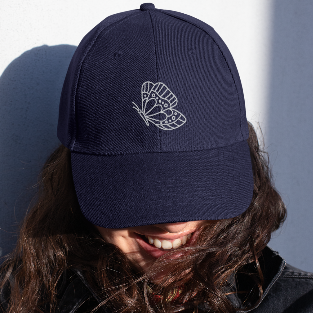 woman wearing navy butterfly embroidered organic cotton cap